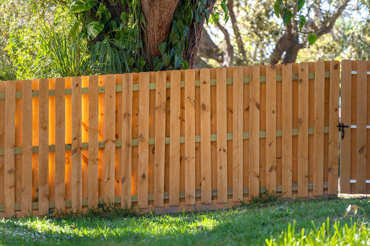 Wooden plank fence in backyard. Timber fencing for grounds protection and privacy.